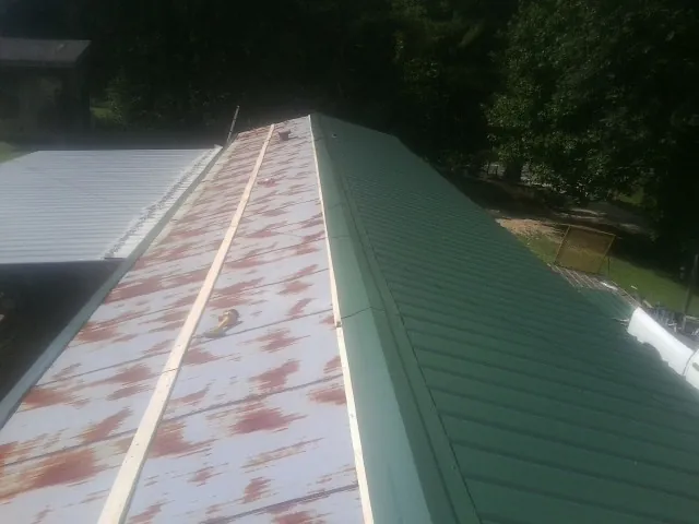 Old rusted panels beside newly installed green metal roofing — Wind Damage Roof Repair by Roofing Brothers in Wellford