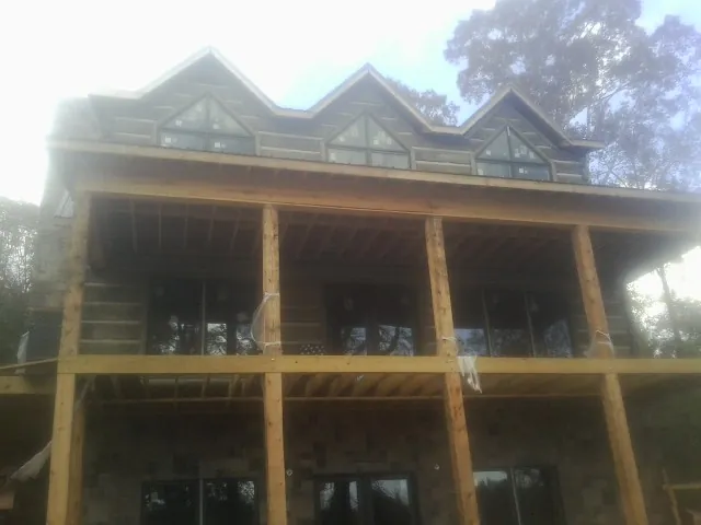Dormers and porch framing on a large log home under construction — Roof Coating work by our crew in Wellford