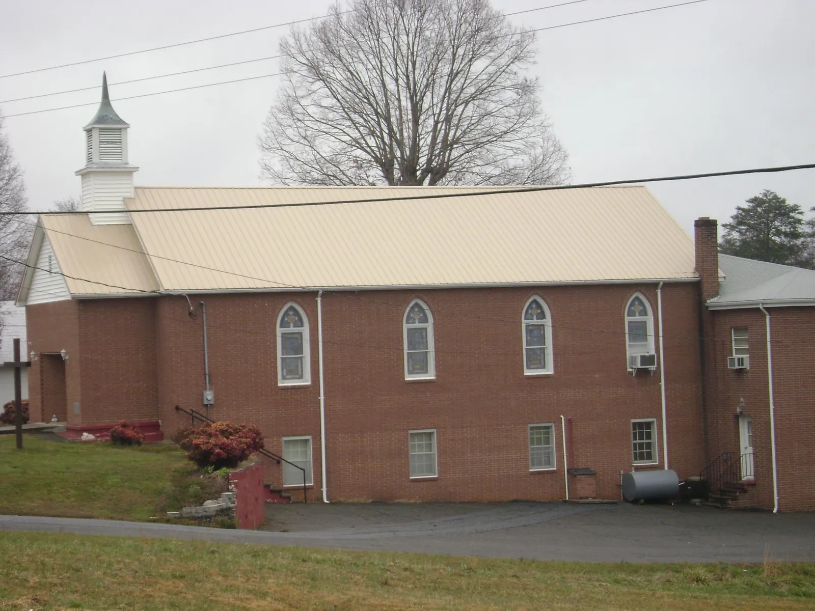 New tan metal roof on a brick church with a white steeple in Wellford