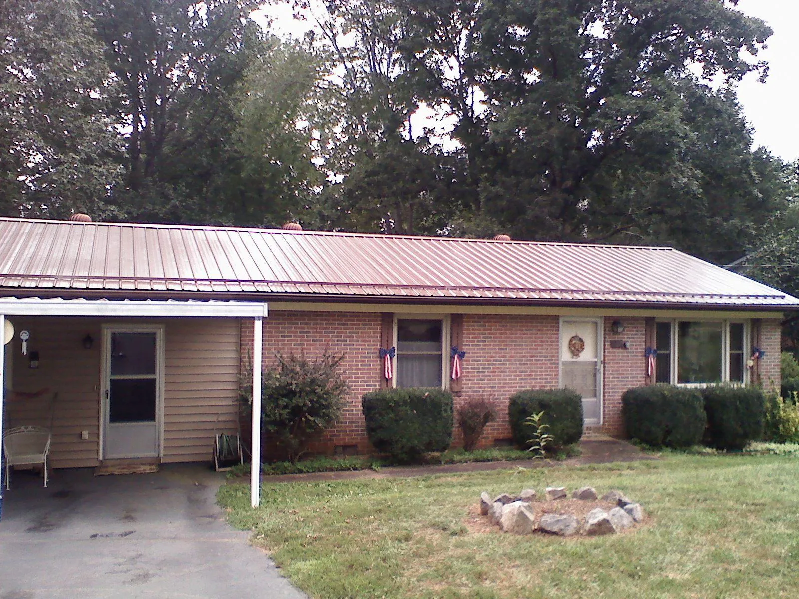 Bronze metal roof and carport on a brick ranch home — Roof Repair work by our crew in Wellford