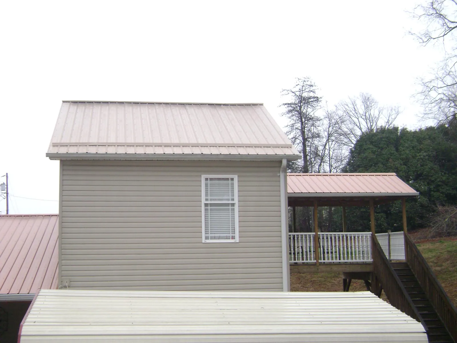 Tan metal roofs on a two story addition and attached porch, from a Roof Replacement job in Wellford