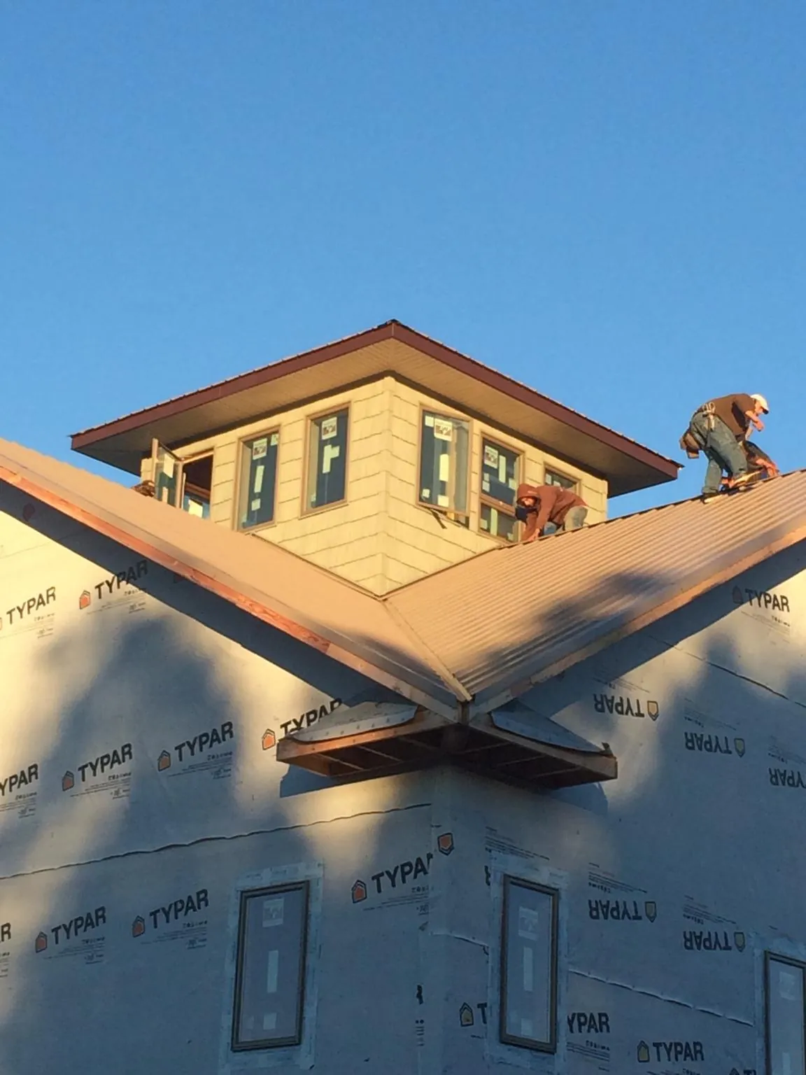 Roofers working around a rooftop cupola on a new metal roof at sunset — Roof Waterproofing in Wellford by Roofing Brothers